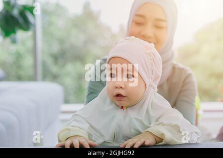 Musulmana Madre guardare il suo bambino felice sorridente infante casa cura insieme carino bella infanzia indoor. Foto Stock