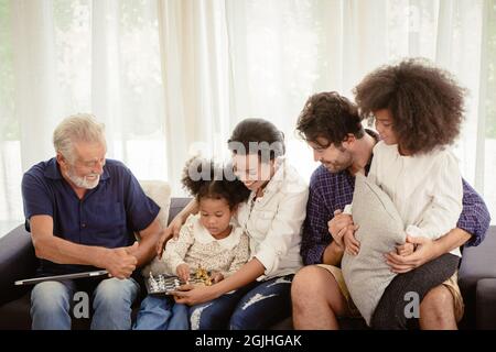 Bella casa famiglia soggiorno insieme in soggiorno padre madre e nonno giocare con la figlia mix razza. Foto Stock