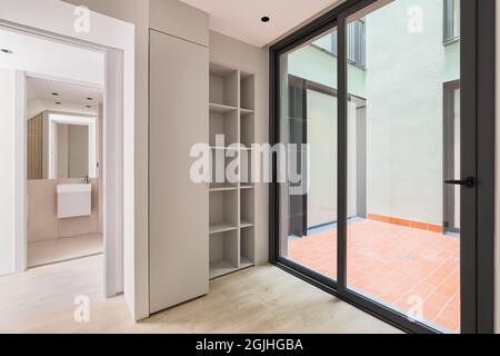 Interno di moderna camera vuota in appartamento ristrutturato con grande cornice nera di finestre, armadio e vista sul bagno. Foto Stock