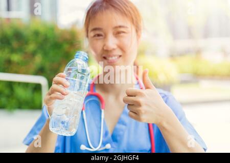 Dottore femminile con acqua potabile per una buona salute in giornata calda per uno stile di vita fresco e sano. Foto Stock