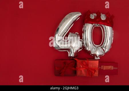 Palloncini argentati 40 quaranta in corona su sfondo rosso scuro. Decorazione festa di festa, 40 concetto di cartolina con vista dall'alto Foto Stock