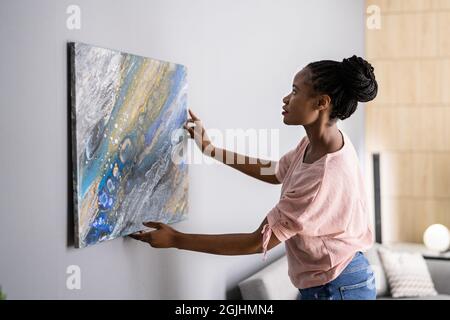 Donna sorridente che appica la pittura o l'immagine all'interno Foto Stock