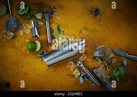 Vista dall'alto del set di attrezzature per barman e lime affettato su un tavolo di legno durante la preparazione del cocktail Foto Stock