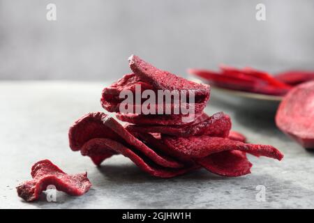 Patatine di barbabietole vegetali su sfondo grigio. Spuntino vegano. Primo piano. Foto Stock