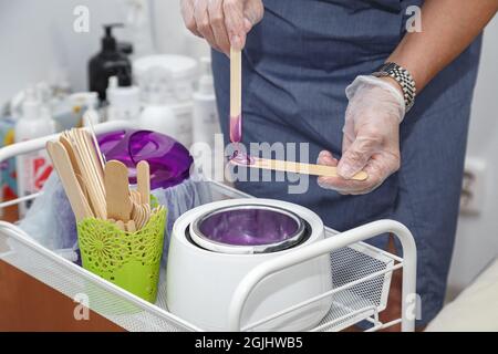 Foto di cera violetta fusa su bastone di legno per depilazione Foto Stock