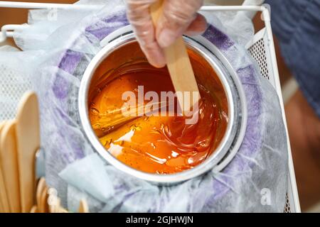 Foto di cera d'oro fusa su bastone di legno per depilazione Foto Stock