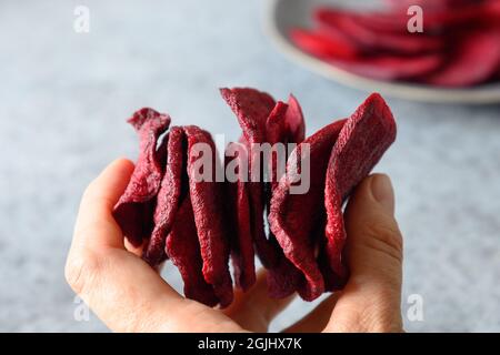 Patatine di barbabietole vegetali in mano. Spuntino vegano. Primo piano. Fast food sano. Foto Stock