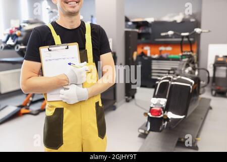 Il meccanico automatico in officina tiene gli appunti per prendere gli ordini in primo piano Foto Stock