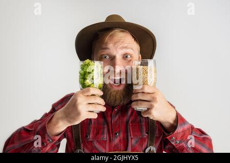 Uomo sorridente felice vestito in costume bavarese tradizionale che tiene bicchieri di birra pieni di caldo selvatico e orzo. Celebrazione, oktoberfest, festival Foto Stock