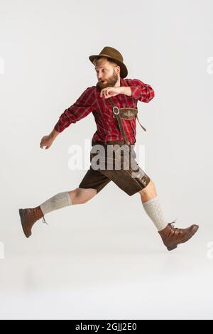 Ritratto a tutta lunghezza di uomo portico in cappello e costume tradizionale bavarese che corre via isolato su sfondo bianco. Volantino, concetto oktoberfest Foto Stock