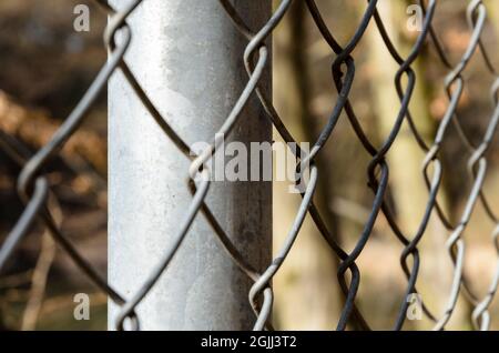 Primo piano di recinzione metallica a catena, modello a diamante, con profondità di campo ridotta o messa a fuoco selettiva, sfondo astratto o sfondo Foto Stock