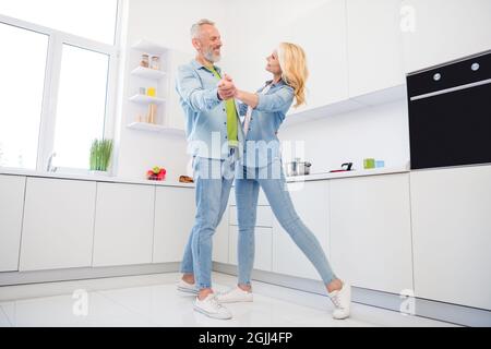 Foto a grandezza naturale di allegro sorridente affascinante coppia sposata moglie marito ballare in cucina in amore rapporti felici Foto Stock