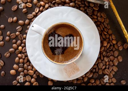 caffè in chicchi sullo sfondo e una tazza di caffè turco fraceo sopra. Messa a fuoco selettiva. Foto Stock