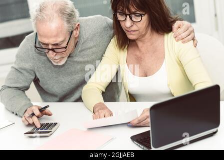 Coppia senior che controlla il documento finanziario a casa Foto Stock