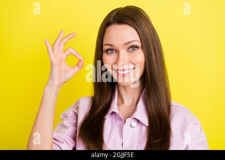 Foto di bruna dolce hairdo millennial donna mostra okey indossare camicia rosa isolato su sfondo giallo Foto Stock