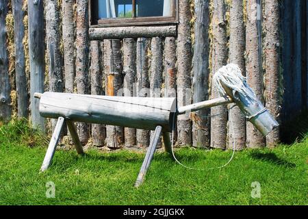 Un antico giocattolo di cavallo hobby in legno, fatto di tronchi, a lato di una cabina di tronchi, Random Passage sito, New Bonaventure, NL. Foto Stock