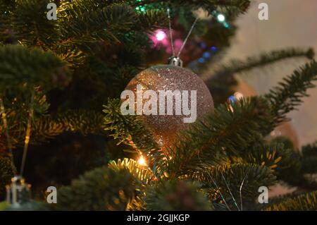 Ornamento glittered di argento di Natale appeso sull'albero artificiale di Natale. Foto Stock