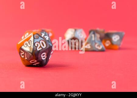 Set di dadi per giochi da tavolo fantasy dnd e rpg. Dadi poliedrici da gioco da tavolo con lati diversi su sfondo rosso brillante Foto Stock