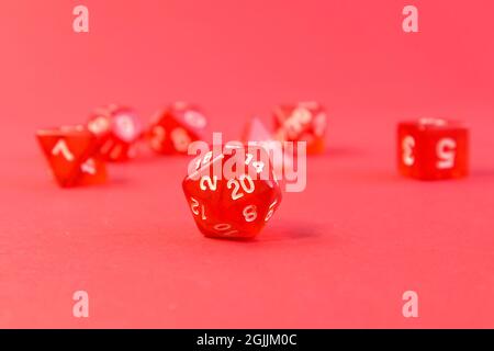 Set di dadi per giochi da tavolo fantasy dnd e rpg. Dadi poliedrici da gioco da tavolo con lati diversi su sfondo rosso brillante Foto Stock