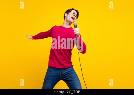 Foto di funky cute giovane Signore indossare rosso pullover occhiale scuro ballare cantando sorridente isolato colore sfondo giallo Foto Stock