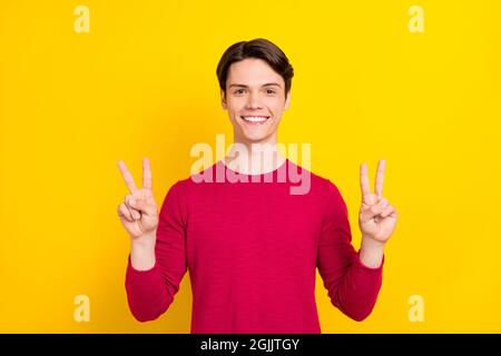 Foto di dolce grazioso giovane Signore indossare maglione rosso mostrando due v-segni sorridente isolato sfondo di colore giallo Foto Stock