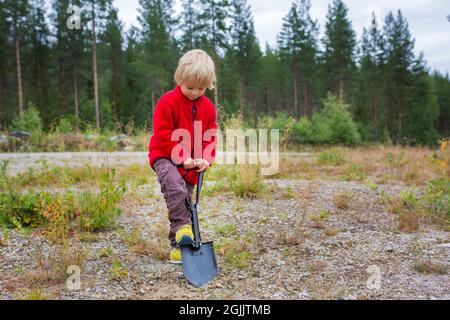 Bambino carino, scavando un buco, pulendo dopo se stesso su un campeggio selvaggio nella foresta Foto Stock