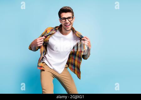 Foto di ragazzo giovane eccitato fresco vestito camicia a quadri sorridente ballando puntando dita isolato blu sfondo di colore Foto Stock
