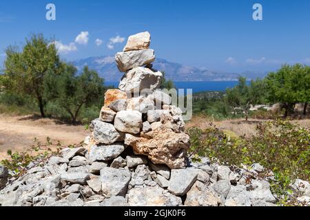 Un cairn che segna un percorso di montagna, un mucchio di pietre artificiali per la navigazione del trekking Foto Stock