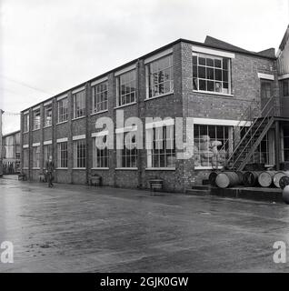 Anni '50, storico, esterno di un edificio industriale prima della seconda Guerra Mondiale, una fabbrica di verniciatura, Inghilterra, Regno Unito. Probabilmente erette negli anni '30, i locali industriali sono in mattoni, basso livello alto solo due piani e con grandi finestre in metallo incorniciate e una scala esterna al primo piano. Foto Stock