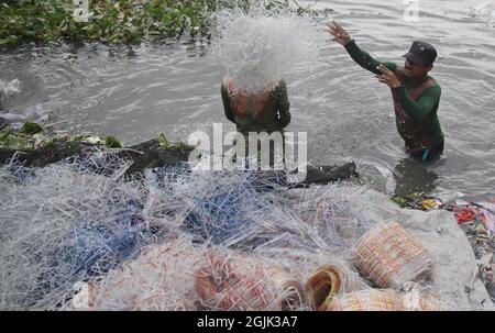 I lavoratori hanno sbattuto l'acqua di stoffa lungo un fiume inquinato. I lavoratori lavano, squillano e asciugano la stoffa lungo le rive del fiume ogni giorno per una retribuzione minima. Il 09 settembre 2021 a Dhaka, Bangladesh. (Foto di Sumit Ahmed / Eyepix Group) Foto Stock