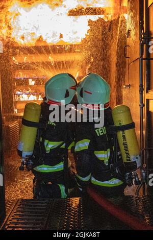 Pirna, Germania. 9 settembre 2021. Due vigili del fuoco si preparano nel contenitore per un flash-over che deve essere spento. Vigili del fuoco del distretto di Sächsische Schweiz-Osterzgebirge su scenari nel contenitore di addestramento del fuoco. Credit: Daniel Schäfer/dpa-Zentralbild/Daniel Schäfer/dpa/Alamy Live News Foto Stock