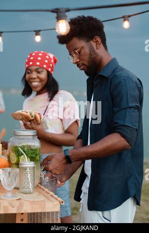 Giovane coppia africana che pranza con panini e beve limonata all'aperto Foto Stock