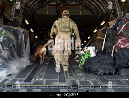 U.S. Air Force staff Sgt. James Terry, 386a Expeditionary Security Forces Squadron militare che lavora cane gestore, conduce una ricerca di afghano evapuee bagaglio con il suo K-9 alla Ali al Salem Air base, Kuwait, 25 agosto 2021. Il Dipartimento della Difesa si impegna a sostenere l'evacuazione dei cittadini americani, dei richiedenti di visti speciali per immigrati e di altri individui a rischio provenienti dall'Afghanistan. (STATI UNITI Air Force foto di staff Sgt. Ryan Brooks) Foto Stock