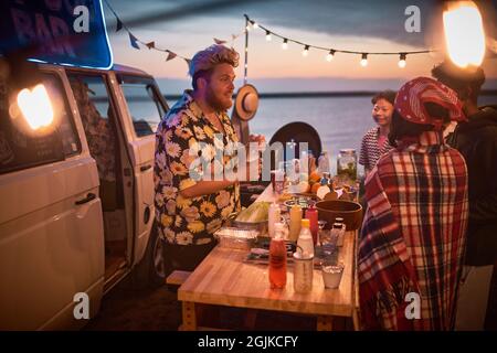 Giovane barman che fa cocktail alcolici per i giovani al Beach party Foto Stock