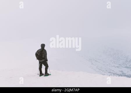 Da soli turistico con uno zaino in alta montagna in inverno. Concetto di viaggio Foto Stock