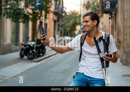 Selfie di giovane latino con stampelle per strada Foto Stock