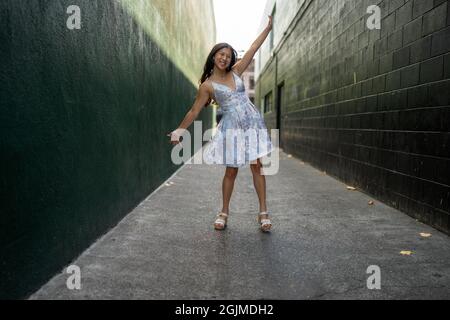 Adolescente Asian Girl gira in abito da festa in un vicolo verde scuro Foto Stock