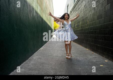 Adolescente Asian Girl gira in abito da festa in un vicolo verde scuro Foto Stock