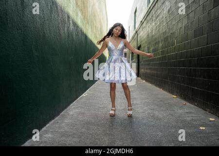 Adolescente Asian Girl gira in abito da festa in un vicolo verde scuro Foto Stock