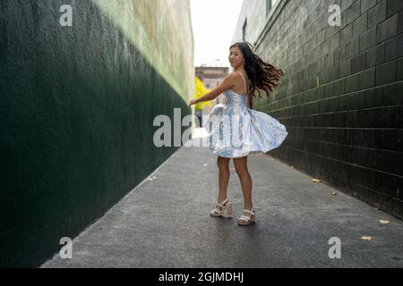 Adolescente Asian Girl gira in abito da festa in un vicolo verde scuro Foto Stock