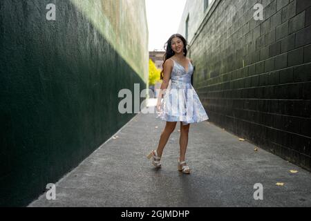 Adolescente Asian Girl gira in abito da festa in un vicolo verde scuro Foto Stock