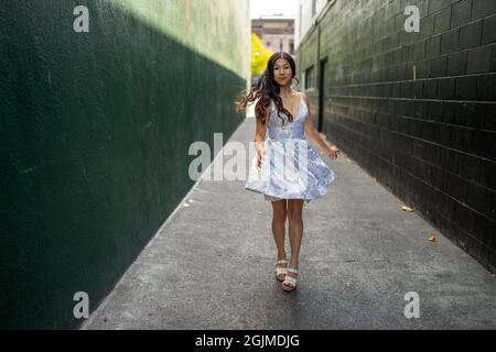 Adolescente Asian Girl gira in abito da festa in un vicolo verde scuro Foto Stock