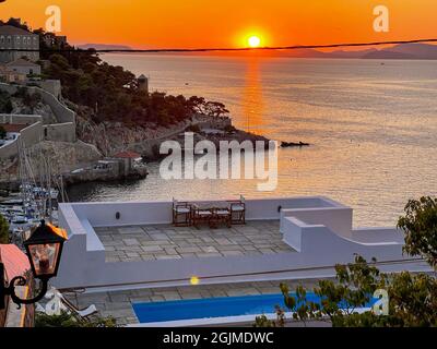 Splendidi colori al tramonto dalla pittoresca isola di Hydra in Grecia. Vista dalla città di Hra sul porto. Foto Stock