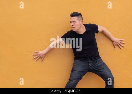 L'uomo temuto con le mani contro il muro che guarda e aspetta qualcosa Foto Stock