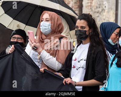 Ragazze arabe con maschere chirurgiche sul loro volto scuotendo una bandiera durante un incontro politico. Foto Stock