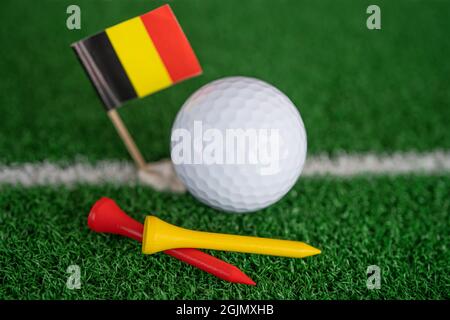 La palla da golf con bandiera tedesca e tee sul prato verde o l'erba è lo sport più popolare al mondo. Foto Stock