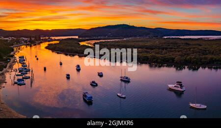 Colorato paesaggio acquatico con tramonto nuvoloso e barche a Woy Woy, NSW, Australia. Foto Stock