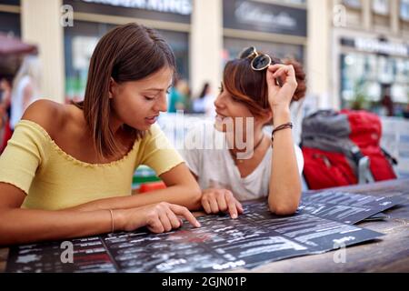 Due amici che ordinano in un caffè insieme dal menu Foto Stock