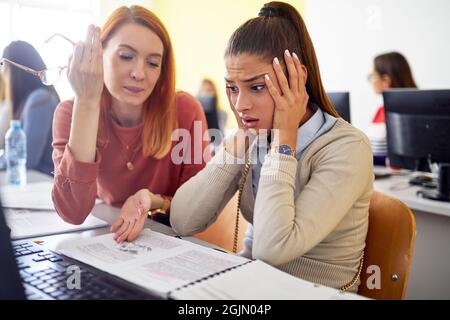 Una studentessa femminile confusa da una nuova lezione di informatica durante la lezione in aula universitaria. I giovani intelligenti studiano all'università. Ed Foto Stock