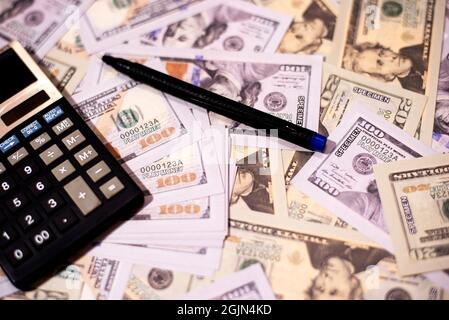 Contando la valuta di carta degli Stati Uniti cento dollari in una calcolatrice su fondo bianco isolato. Foto Stock